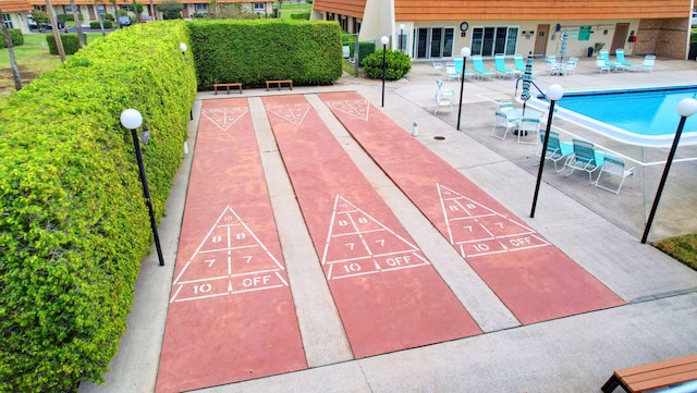 view of home's community with shuffleboard and a patio