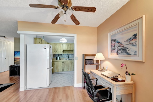 office area featuring light wood-style flooring, a textured ceiling, a ceiling fan, and a sink