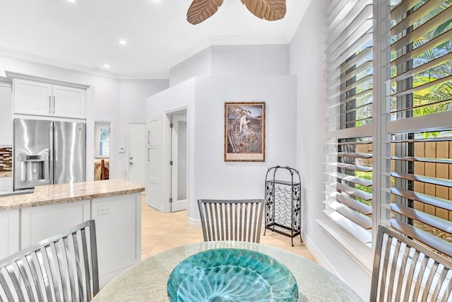 kitchen featuring crown molding, plenty of natural light, white cabinets, and stainless steel refrigerator with ice dispenser