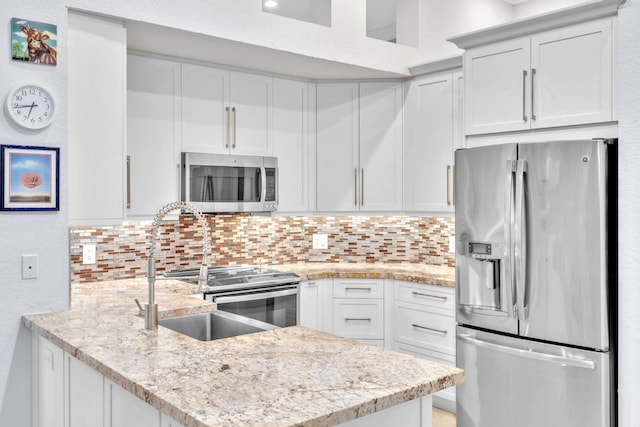 kitchen with white cabinets, light stone counters, backsplash, and appliances with stainless steel finishes