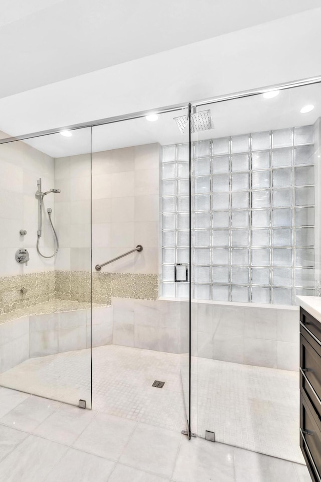 bathroom featuring tile patterned flooring, vanity, and a tile shower