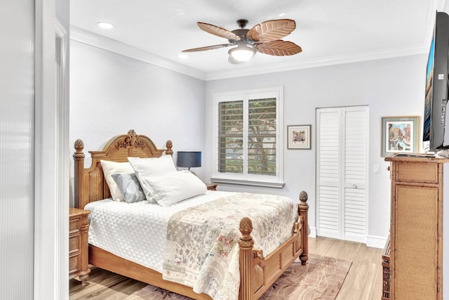 bedroom featuring ceiling fan, light hardwood / wood-style floors, ornamental molding, and a closet