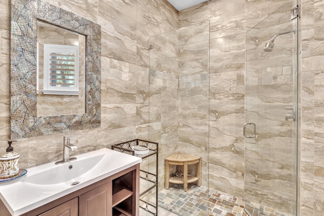 bathroom featuring vanity, a shower with door, and tile walls