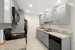 kitchen featuring sink, black appliances, and light stone countertops