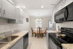 kitchen with white cabinetry, sink, light hardwood / wood-style floors, and black appliances