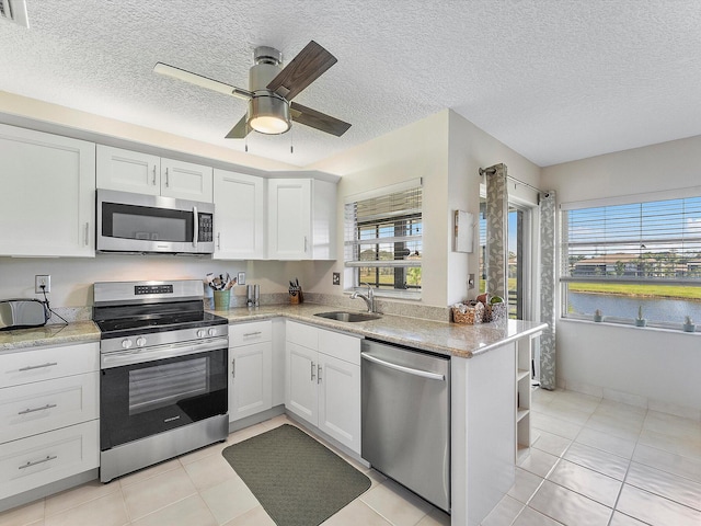 kitchen with kitchen peninsula, a healthy amount of sunlight, white cabinets, and stainless steel appliances