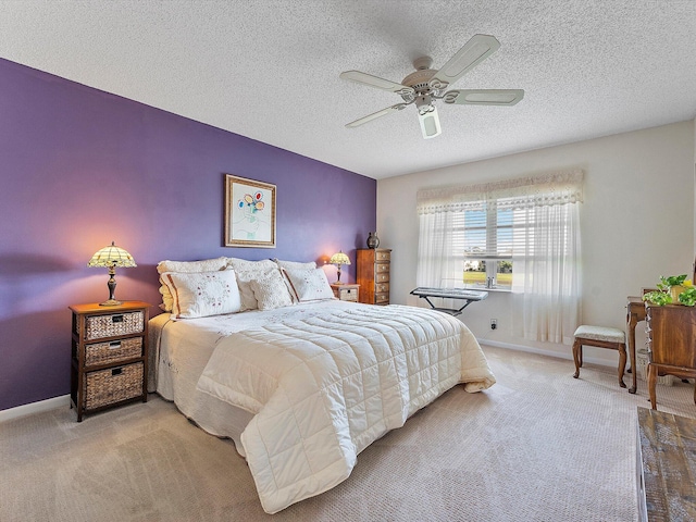 bedroom featuring ceiling fan, light colored carpet, and a textured ceiling