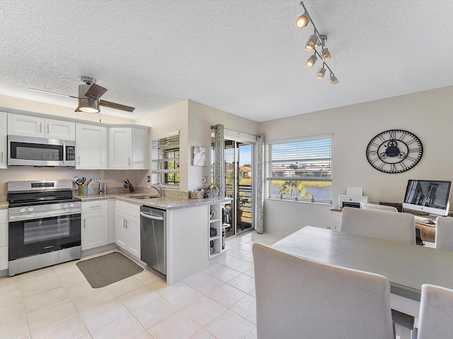 kitchen featuring kitchen peninsula, appliances with stainless steel finishes, a textured ceiling, sink, and white cabinetry