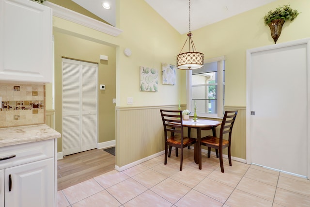 tiled dining area featuring high vaulted ceiling