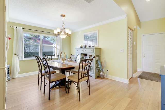 dining space with crown molding, light wood-type flooring, a textured ceiling, and an inviting chandelier