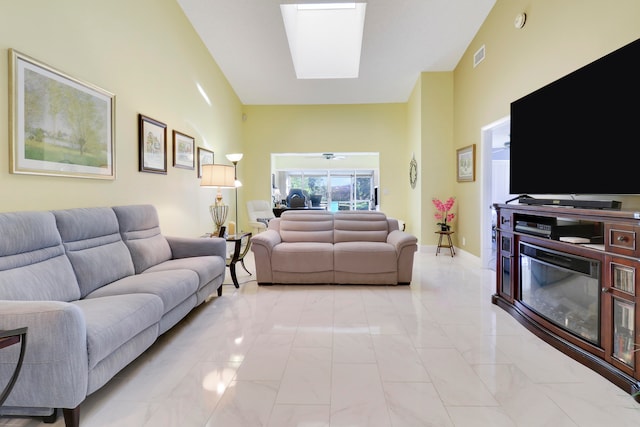 living room featuring a skylight, ceiling fan, and a towering ceiling