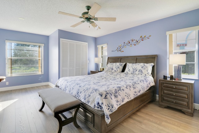 bedroom featuring ceiling fan, light wood-type flooring, a textured ceiling, and a closet