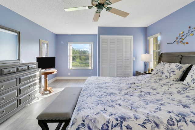 bedroom with ceiling fan, a closet, a textured ceiling, and light wood-type flooring