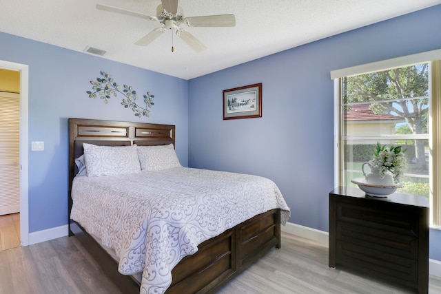 bedroom with hardwood / wood-style floors, a textured ceiling, and ceiling fan