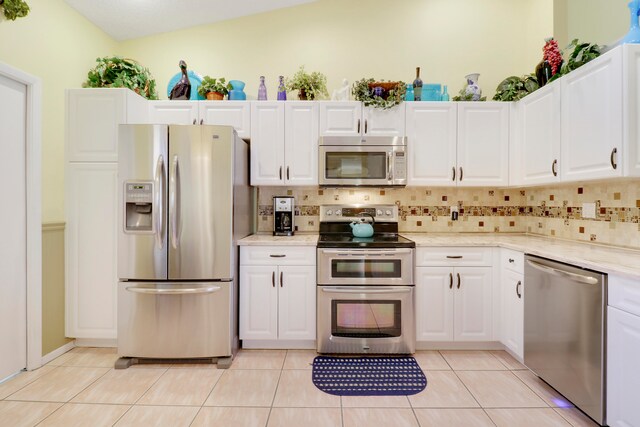 kitchen featuring white cabinets, light tile patterned floors, stainless steel appliances, and lofted ceiling