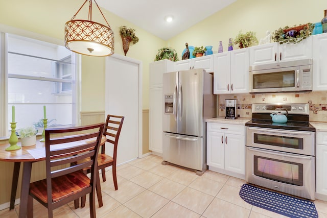 kitchen featuring hanging light fixtures, vaulted ceiling, appliances with stainless steel finishes, tasteful backsplash, and white cabinetry