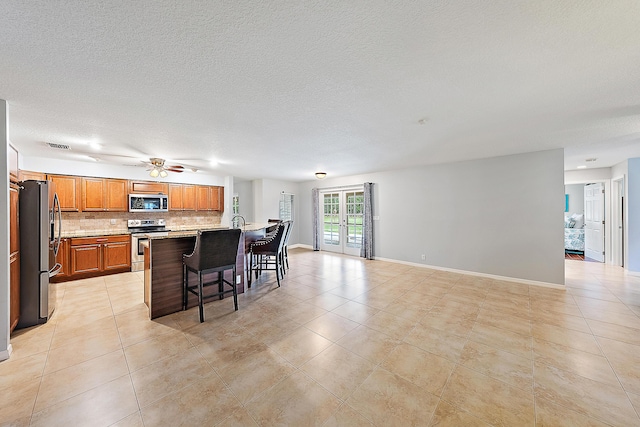 kitchen with light tile patterned floors, decorative backsplash, appliances with stainless steel finishes, and a breakfast bar area