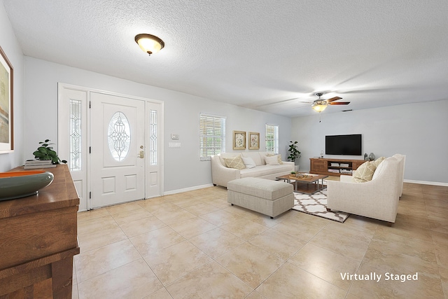 living room featuring light tile patterned floors, baseboards, a textured ceiling, and ceiling fan