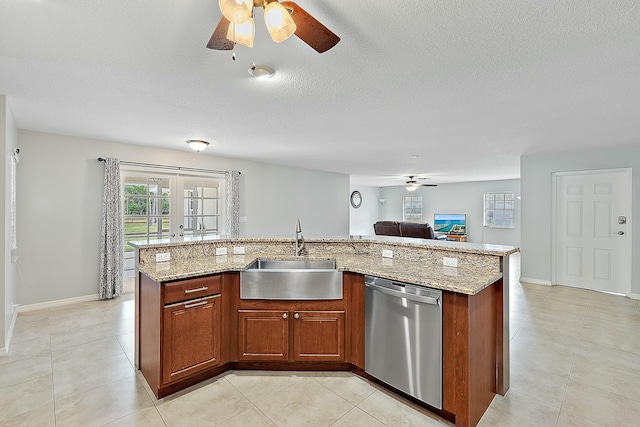 kitchen with light stone countertops, a sink, open floor plan, dishwasher, and brown cabinets