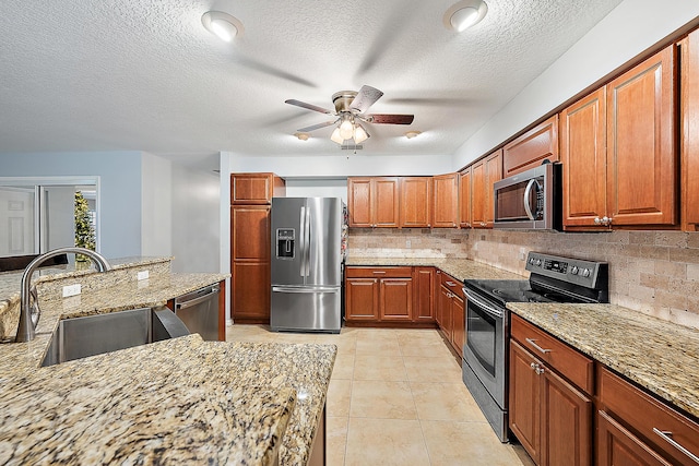 kitchen featuring light stone counters, backsplash, stainless steel appliances, and a sink