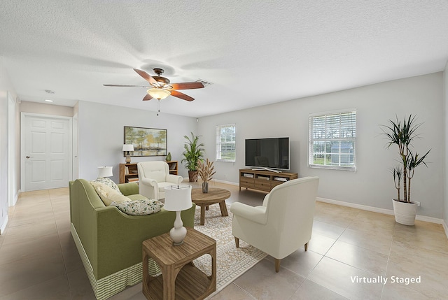 living area featuring baseboards, a textured ceiling, ceiling fan, and light tile patterned flooring