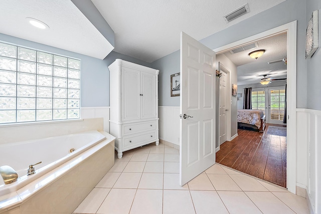 bathroom featuring ceiling fan, tile patterned flooring, a bath, a textured ceiling, and french doors