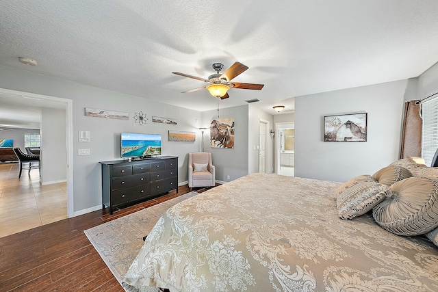 bedroom featuring a ceiling fan, visible vents, wood finished floors, baseboards, and a textured ceiling