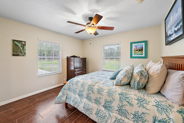 bedroom featuring multiple windows, baseboards, dark wood-style flooring, and a textured ceiling