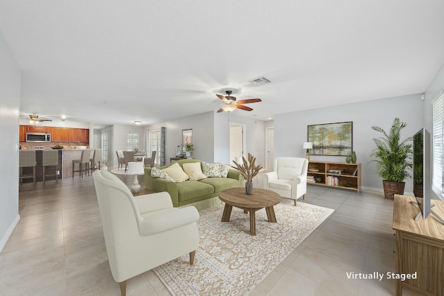 living room featuring plenty of natural light, visible vents, and ceiling fan