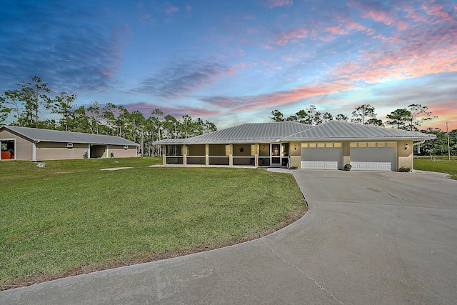 view of front facade featuring a front yard, an attached garage, a sunroom, concrete driveway, and metal roof