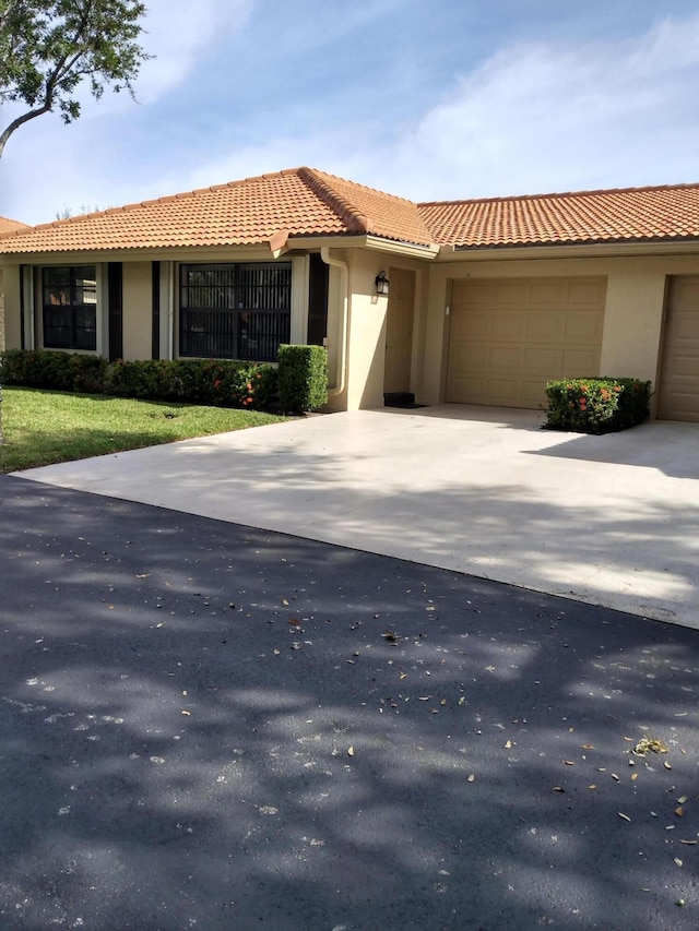9890 Bischofia Tree Way Unit A, Boynton Beach, FL 33436 - view of front of house with a garage, driveway, stucco siding, and a tile roof