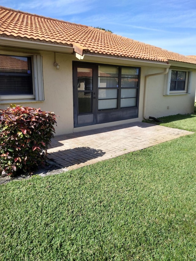 entrance to property featuring a patio area and a yard