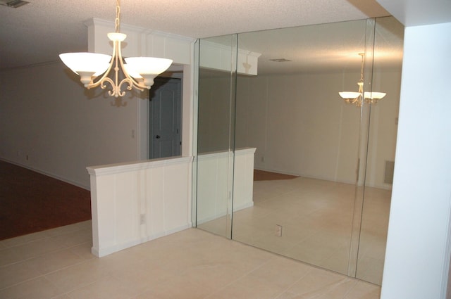 interior space with a textured ceiling, an inviting chandelier, and light tile patterned floors