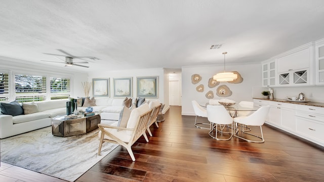 living room with ceiling fan, dark hardwood / wood-style flooring, and crown molding