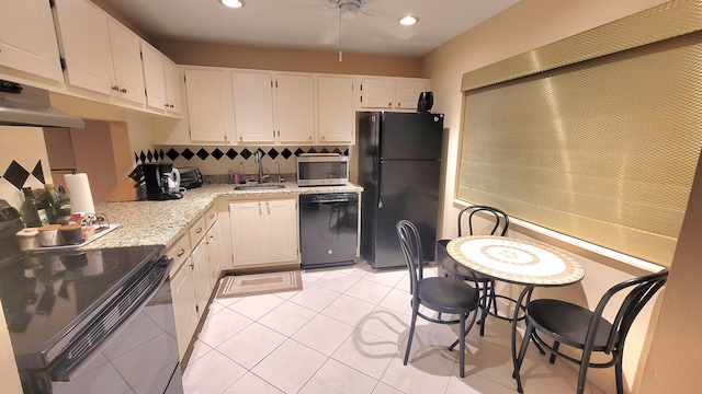 kitchen featuring black appliances, sink, light stone countertops, light tile patterned floors, and white cabinetry