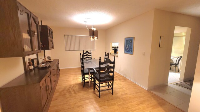 dining area featuring a textured ceiling and light wood-type flooring