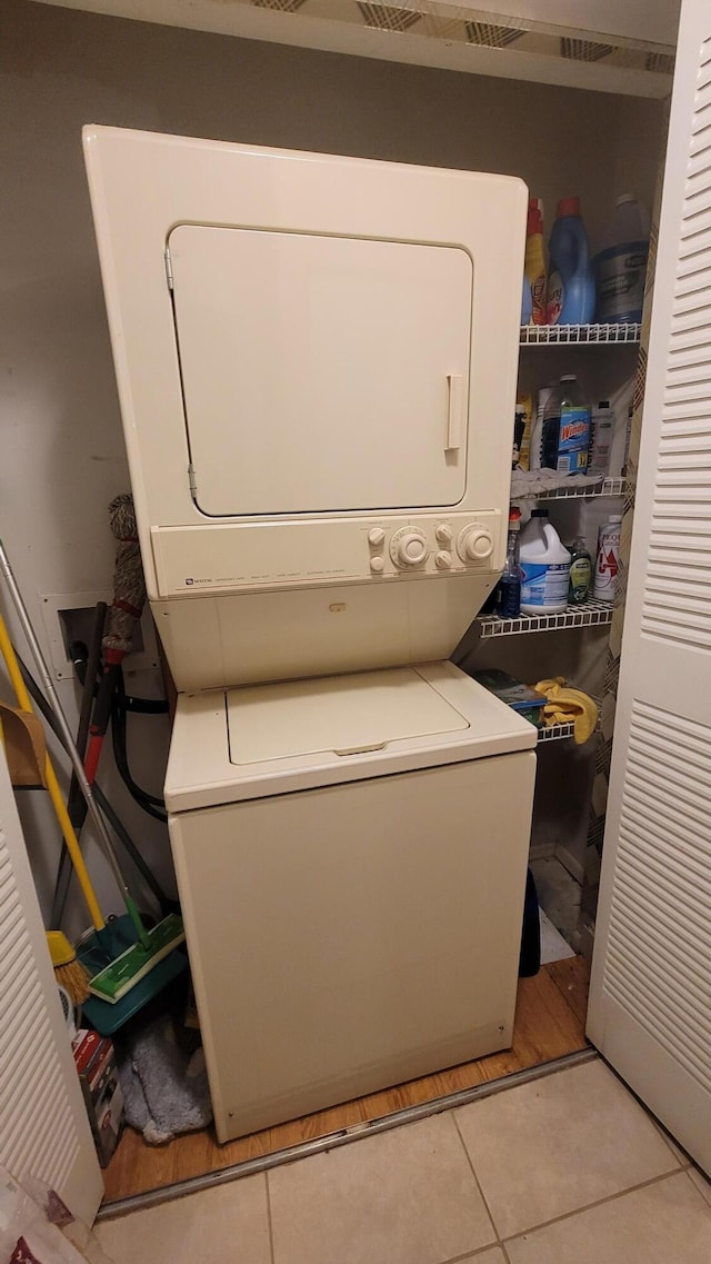 laundry room featuring stacked washing maching and dryer and light tile patterned floors