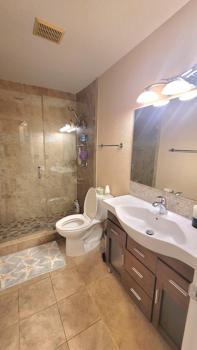 bathroom featuring tile patterned floors, a textured ceiling, toilet, vanity, and a shower with shower door