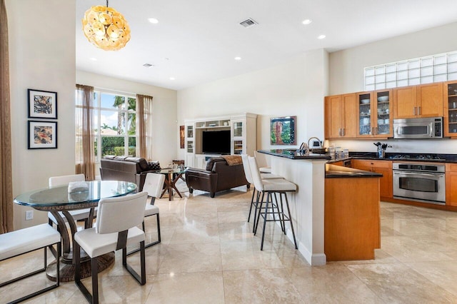 kitchen with pendant lighting, a kitchen breakfast bar, sink, appliances with stainless steel finishes, and kitchen peninsula