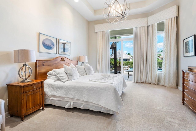 bedroom featuring access to exterior, a raised ceiling, light colored carpet, and an inviting chandelier