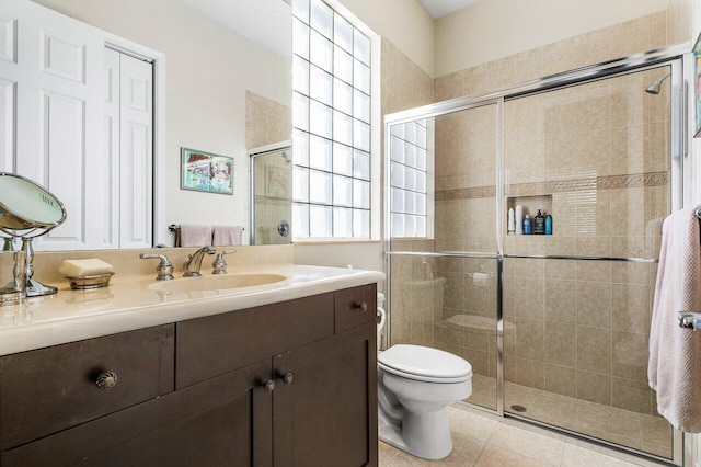 bathroom featuring tile patterned flooring, vanity, toilet, and walk in shower