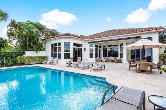 rear view of house featuring an outdoor living space, a fenced in pool, and a patio area