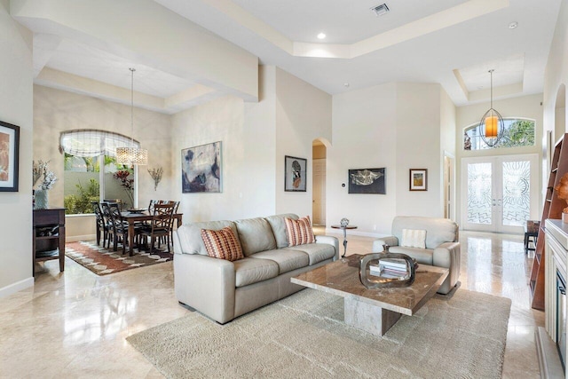 living room with french doors, a tray ceiling, and plenty of natural light