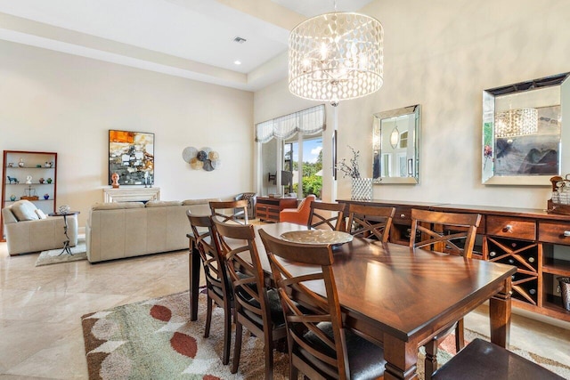 dining area with a tray ceiling, a high ceiling, and a chandelier