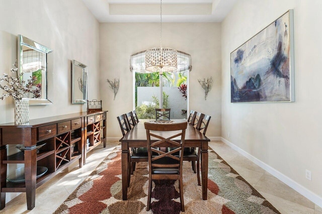 dining room with a notable chandelier, a high ceiling, and a tray ceiling