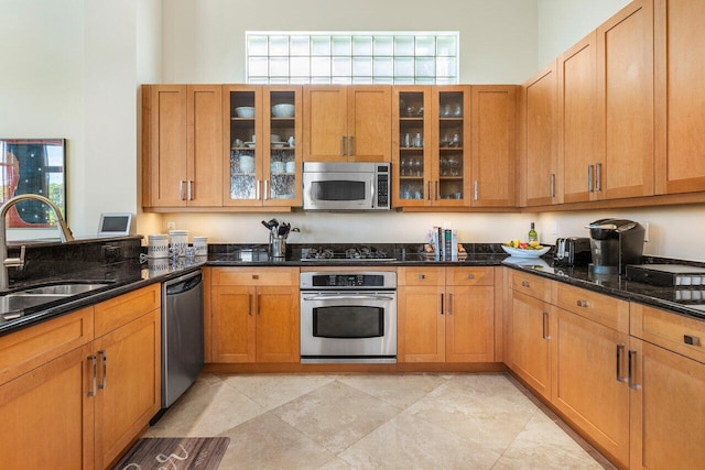 kitchen featuring appliances with stainless steel finishes, dark stone counters, and sink