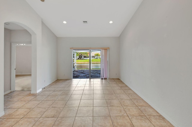 empty room featuring light tile patterned flooring and vaulted ceiling