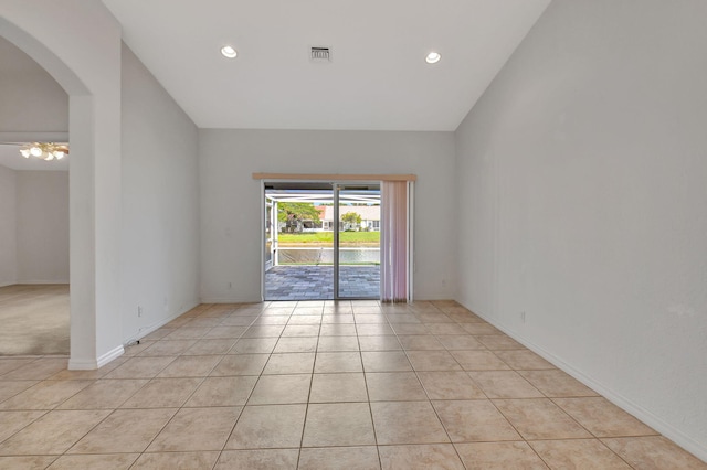 unfurnished room with light tile patterned flooring and lofted ceiling