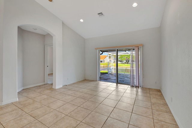 tiled empty room featuring vaulted ceiling