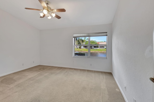 carpeted empty room featuring ceiling fan, a water view, and lofted ceiling